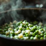Piselli che cuociono in pentola con cipolla.