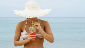 Donna al mare che beve una bibita