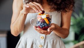 Donna con un bicchiere pieno di frutta colorata