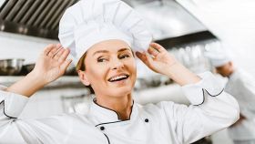 Donna sorridente si sistema il cappello da chef