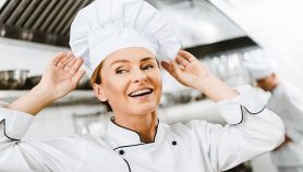 Donna sorridente si sistema il cappello da chef