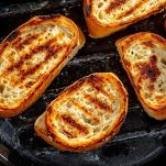 Abbrustolite leggermente le fette di pane su una brace o su una griglia fino a renderle croccanti e dorate.