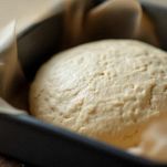 Impasto disposto in teglia rivestita di carta forno.