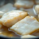 Filetti di baccalà che cuociono nella casseruola.