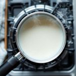 Pentolino con latte intero che raggiunge il punto di ebollizione sul fornello