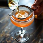 Cocktail filtrato dallo shaker e versato in una coppetta precedentemente raffreddata