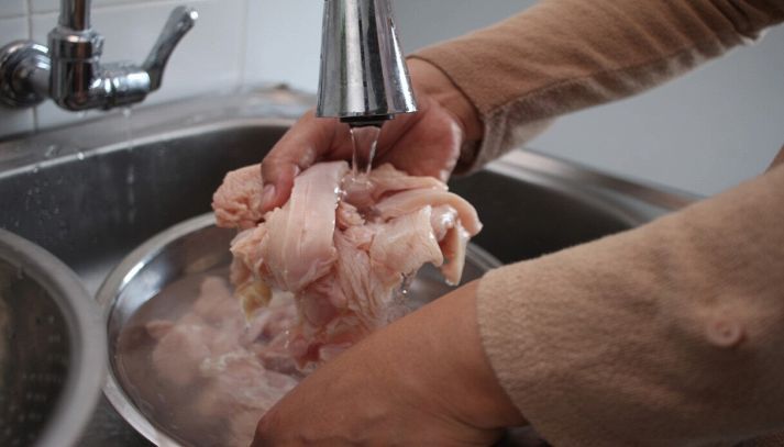 Lavare il pollo crudo sotto l'acqua corrente
