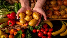 Mani con patate e ortaggi e frutta sullo sfondo
