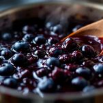 Pentola con marmellata di mirtilli in cottura mentre viene mescolata
