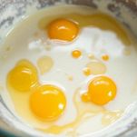 Uova e latte mescolati in ciotola.