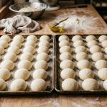 Panini crudi disposti ordinatamente sulla teglia.