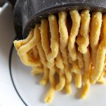 Passatelli estrusi con schiacciapatate sul tagliere