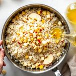 Padella con riso e mela mentre vengono mescolati durante la tostatura