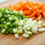 Tagliere con cipollotti e carote affettate