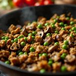 Salsiccia sbriciolata con funghi e piselli in padella