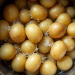 Pentola con patate bollite poi passate nello schiacciapatate