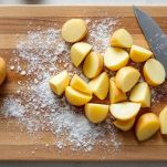 Tagliere con patate tagliate in pezzi uniformi