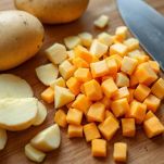 Tagliere con patate e zucca a pezzi e cipolla tritata