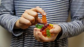 Bambino tiene in mano caramelle gommose a forma di orsetto