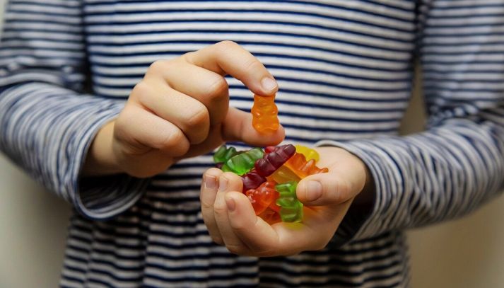 Bambino tiene in mano caramelle gommose a forma di orsetto