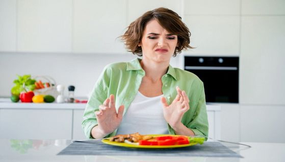 Donna disgustata da un piatto di verdure