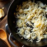 Cipolle bianche sottili che appassiscono lentamente con burro e olio