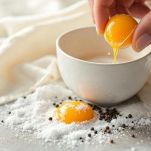 Uova crude rotte in ciotola con sale e pepe