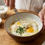 Ricotta con uovo e Parmigiano mescolati in una ciotola fino a ottenere un composto cremoso.
