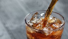 Versare la Coca Cola in un bicchiere di vetro con ghiaccio