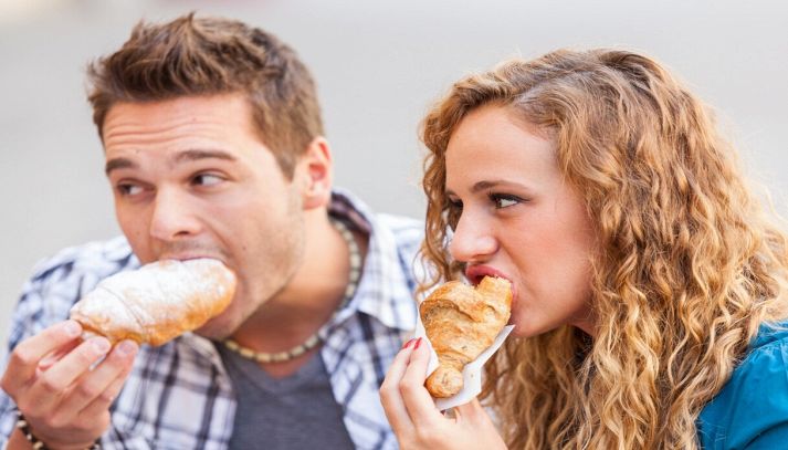 Coppia fa colazione col cornetto al bar