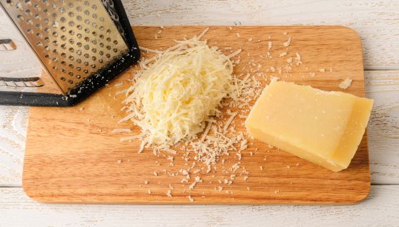 Formaggio grattugiato fresco su tagliere di legno