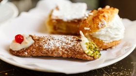 Cannolo siciliano con altri dolci sullo sfondo