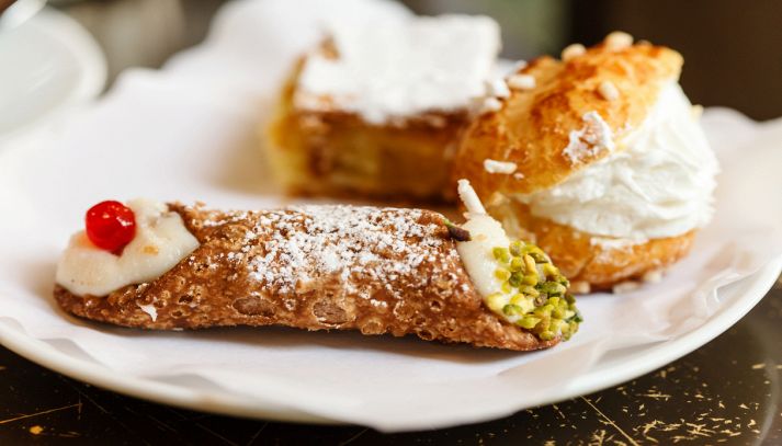 Cannolo siciliano con altri dolci sullo sfondo