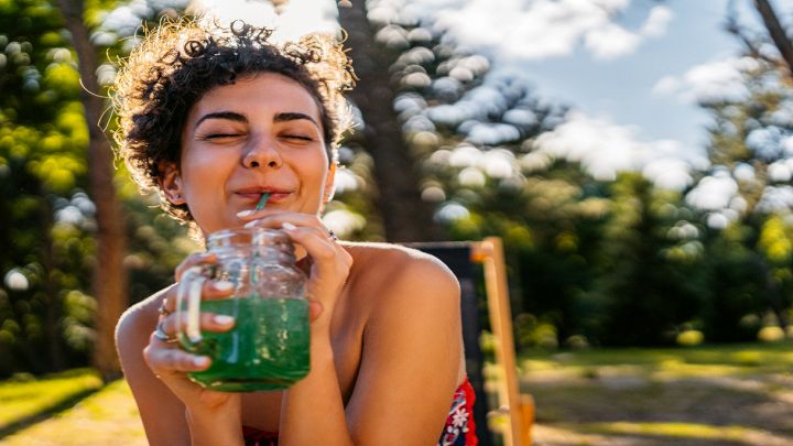 Donna sorridente beve un succo verde