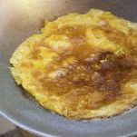 Girate la frittata utilizzando un piatto o un coperchio fatela scivolare e capovolgetela. Cuocete altri 3–4 minuti.
