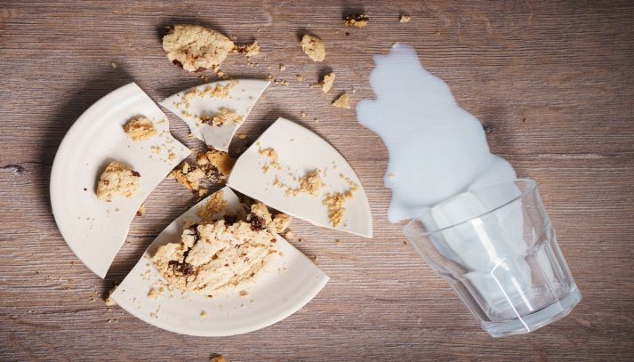 Piatto rotto con cibo e bicchiere di latte rovesciato