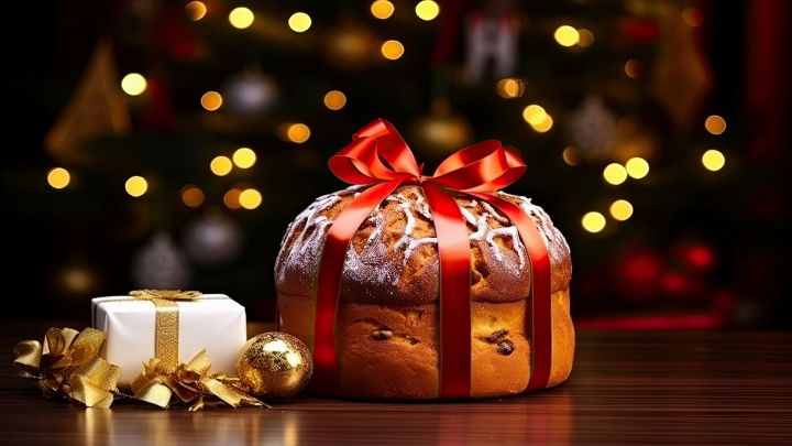 Panettone di Natale con fiocco e luci sullo sfondo