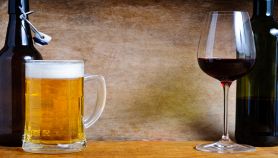 Boccale di birra e calice di vino rosso appoggiati su tavolo di legno