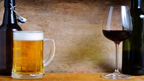 Boccale di birra e calice di vino rosso appoggiati su tavolo di legno