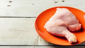 Coscia di pollo cruda su piatto arancione
