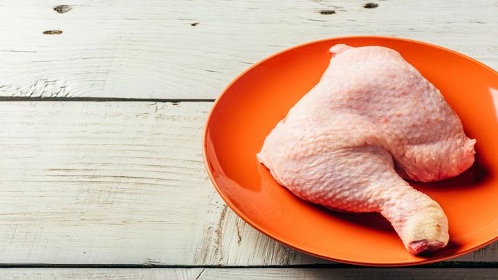 Coscia di pollo cruda su piatto arancione