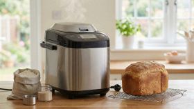 Macchina del pane in acciaio su piano cucina con pagnotta dorata su griglia.