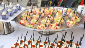 Buffet di finger food con coppette monoporzione di frutta fresca e dessert, servite con piccoli cucchiaini neri da aperitivo.