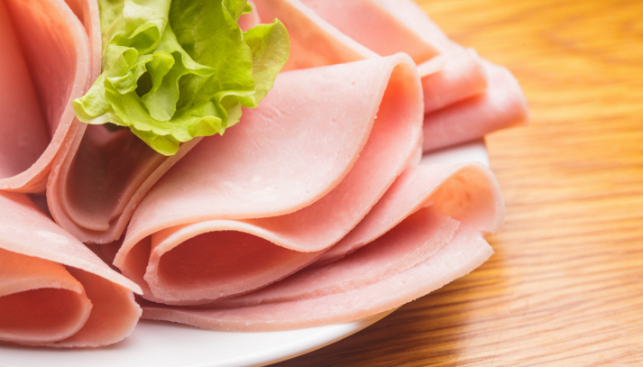 Fette di prosciutto cotto e altri salumi confezionati, simbolo delle carni lavorate e del dibattito su conservanti e rischio per la salute