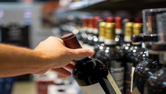 Uomo acquista una bottiglia di vino al supermercato