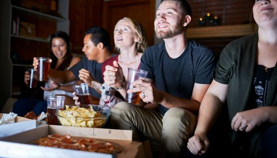 Party amici che guardano Sanremo 2026 e mangiano