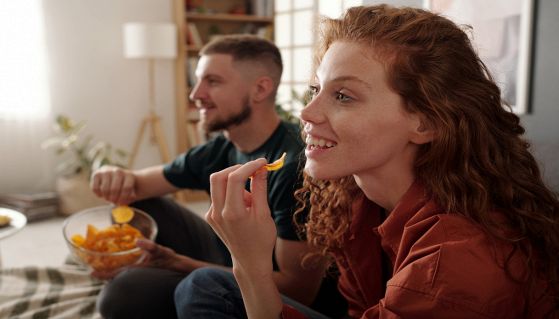 Coppia mangia chips di zucca mentre guarda la tv