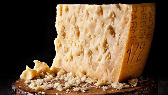 Un pezzo di forma di Parmigiano Reggiano su tagliere