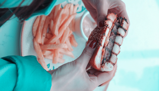 Snack confezionati e bevande zuccherate su un tavolo con etichette ingredienti in vista, simbolo di cibi ultra-processati e consumo abituale