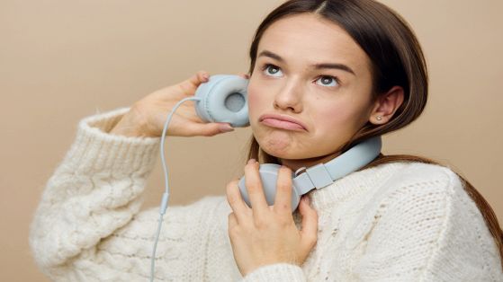Ragazza ascolta la musica con le cuffie e appare insoddisfatta